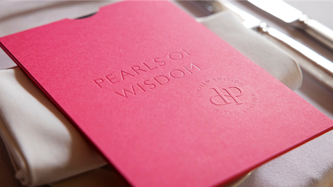 A pink menu on a dinner table at Design Podge, featuring the text 'Pearls of Wisdom'