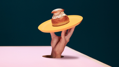 Hand holding up a choux bun on a plate